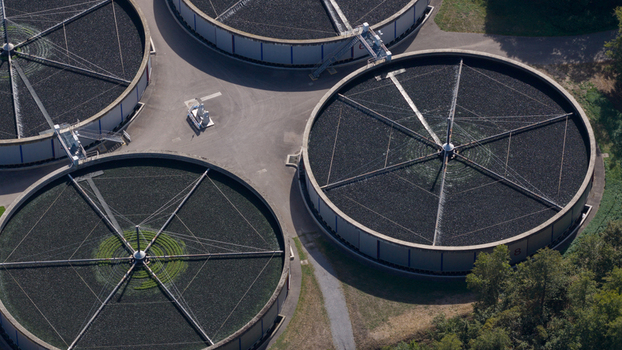 Aerial view of circular sedimentation tanks at the Klarwerk Karlsruhe wastewater treatment plant with industrial infrastructure and greenery in Karlsruhe Baden Wurttemberg Germany.