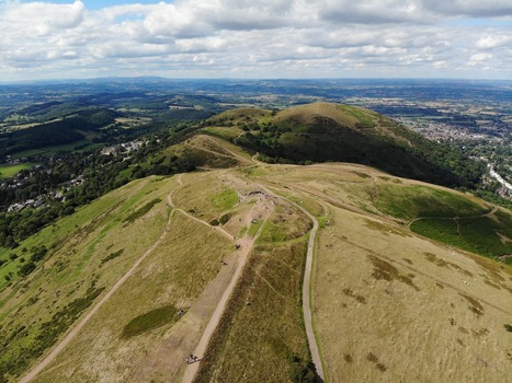 Aerial view of the rolling grassy slopes and winding footpaths of the Malvern Hills under a cloudy sky in Malvern England United Kingdom.