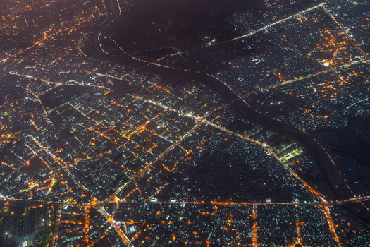 Aerial view of the illuminated city grid and winding river at night in Karachi Sindh Pakistan.