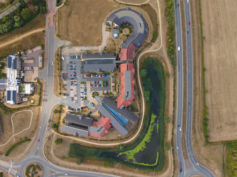 Aerial view of the unique architecture of Wixams Retirement Village with its curved buildings red roofs central parking area and adjacent pond in Bedford England United Kingdom.