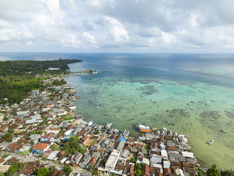 Aerial view of the vibrant coastal village where the earthy tones of the rooftops meet the turquoise embrace of the sea Karimunjawa Central Java Indonesia. Aerial view of the vibrant coastal village where the earthy tones of the rooftops meet the turquoise embrace of the sea Karimunjawa Central Java Indonesia.