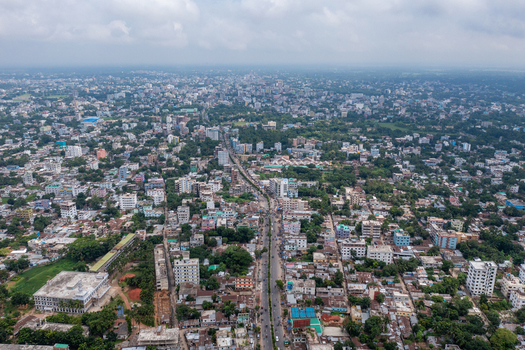 Aerial view of dense urban development residential buildings commercial structures and a main road running through the center in Bogura Rajshahi Division Bangladesh. Aerial view of dense urban development residential buildings commercial structures and a main road running through the center in Bogura Rajshahi Division Bangladesh.
