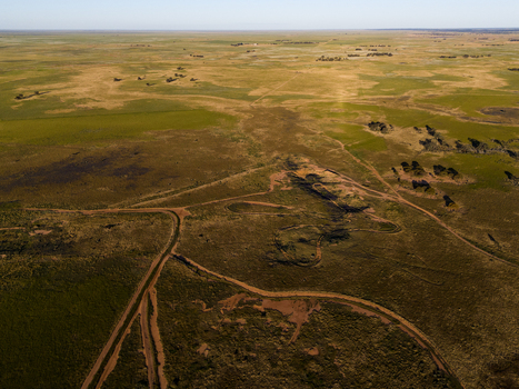 Aerial view of the vast arid flat landscape of the Australian outback with sparse vegetation dirt tracks and shadows cast across the plains in Hay New South Wales Australia.