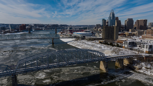 Aerial view of the Cincinnati skyline and the Ohio River filled with floating ice chunks featuring historic bridges and snow covered riverbanks under a clear sky Cincinnati Ohio United States. Aerial view of the Cincinnati skyline and the Ohio River filled with floating ice chunks featuring historic bridges and snow covered riverbanks under a clear sky Cincinnati Ohio United States.