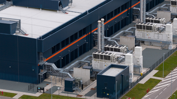 Aerial view of the Agriport industrial facility featuring dark blue buildings with orange stripes and complex cooling systems in Middenmeer Noord Holland Netherlands. Aerial view of the Agriport industrial facility featuring dark blue buildings with orange stripes and complex cooling systems in Middenmeer Noord Holland Netherlands.
