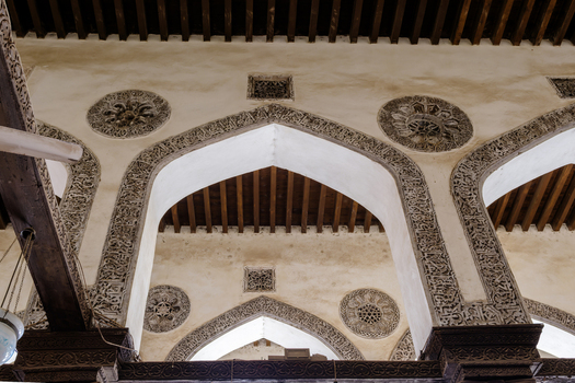View of the Mosque of al Salih Tala i showing the intricate stone carvings on pointed arches and traditional wooden ceiling beams in Cairo Egypt. View of the Mosque of al Salih Tala i showing the intricate stone carvings on pointed arches and traditional wooden ceiling beams in Cairo Egypt.