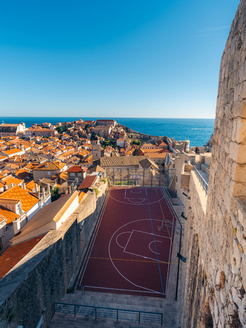 View of the iconic basketball court within the historic stone walls overlooking orange rooftops and the blue sea in Dubrovnik Dubrovnik Neretva County Croatia. View of the iconic basketball court within the historic stone walls overlooking orange rooftops and the blue sea in Dubrovnik Dubrovnik Neretva County Croatia.