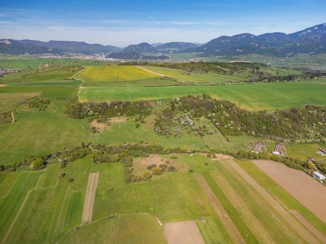 Aerial view of lush green fields and rolling hills with mountains in the background under a clear blue sky in Partizanska Lupca Zilina Region Slovakia.