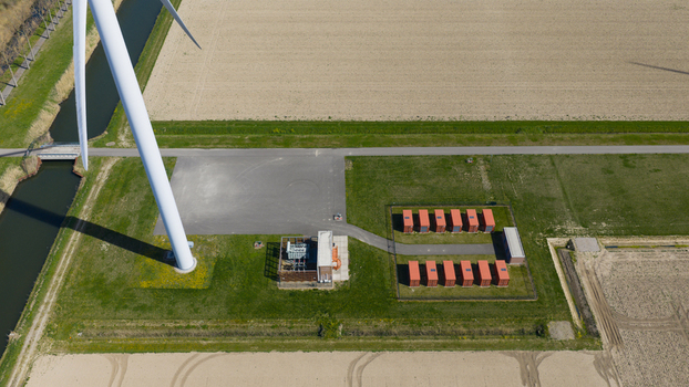 Aerial view of Energiepark Haringvliet Zuid featuring a wind turbine battery storage units and a transformer station amidst green fields in Middelharnis South Holland Netherlands.