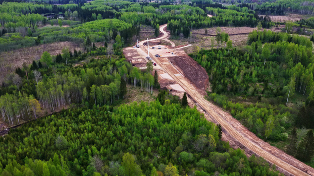 Aerial view of a wind turbine maintenance access road cutting through a dense green forest in Latvija. Aerial view of a wind turbine maintenance access road cutting through a dense green forest in Latvija.