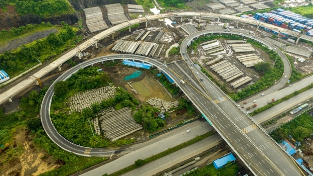 Aerial view of the JNPT Interchange featuring complex highway loops construction materials and surrounding greenery in Navi Mumbai Maharashtra India. Aerial view of the JNPT Interchange featuring complex highway loops construction materials and surrounding greenery in Navi Mumbai Maharashtra India.