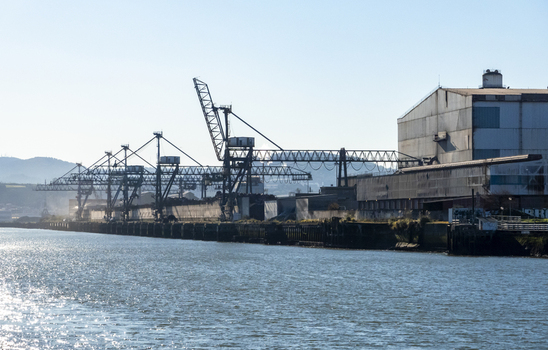 View of the industrial port with large metal cranes and factory buildings along the Nervion river Greater Bilbao Basque Country Spain. View of the industrial port with large metal cranes and factory buildings along the Nervion river Greater Bilbao Basque Country Spain.