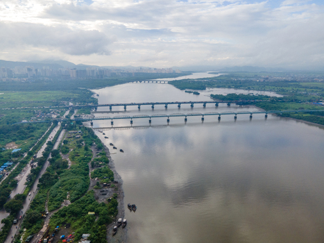 Aerial view of the bridges spanning across the Thane Creek with lush green banks and an urban skyline in the distance in Thane Maharashtra India. Aerial view of the bridges spanning across the Thane Creek with lush green banks and an urban skyline in the distance in Thane Maharashtra India.