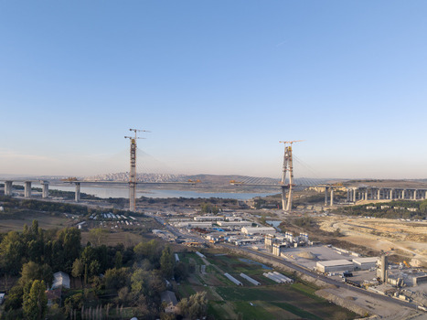 Aerial view of a large suspension bridge under construction with tall pylons cranes and surrounding landscape in Istanbul Istanbul Turkiye.