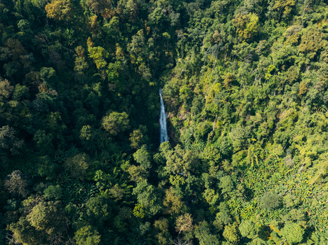 Aerial view of Khun Korn Waterfall cascading down a rocky cliff surrounded by lush tropical forest and dense green foliage Tambon Huai Chomphu Chang Wat Chiang Rai Thailand. Aerial view of Khun Korn Waterfall cascading down a rocky cliff surrounded by lush tropical forest and dense green foliage Tambon Huai Chomphu Chang Wat Chiang Rai Thailand.
