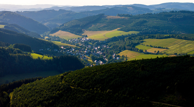 Aerial view of the town of Eslohe nestled in a lush green valley surrounded by dense forests and rolling hills in the Sauerland region Eslohe North Rhine Westphalia Germany. Aerial view of the town of Eslohe nestled in a lush green valley surrounded by dense forests and rolling hills in the Sauerland region Eslohe North Rhine Westphalia Germany.