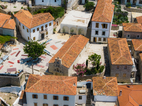 Aerial view of the traditional stone buildings and a small church with orange tiled roofs in the historic village square of Dhermi Vlore County Albania. Aerial view of the traditional stone buildings and a small church with orange tiled roofs in the historic village square of Dhermi Vlore County Albania.