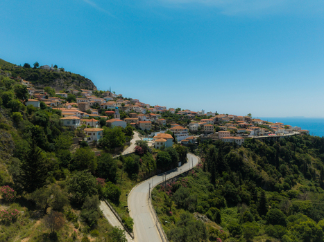 Aerial view of the coastal village of Dhermi featuring traditional houses with red roofs and a winding road along the lush green hillside in Dhermi Vlore County Albania. Aerial view of the coastal village of Dhermi featuring traditional houses with red roofs and a winding road along the lush green hillside in Dhermi Vlore County Albania.
