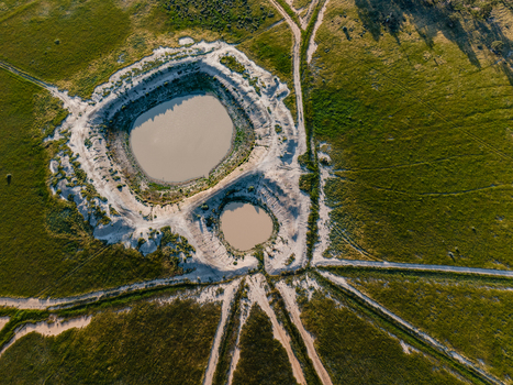 Aerial view of two circular ponds in a flat landscape with radiating dirt tracks in Hay New South Wales Australia.