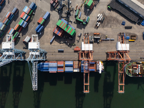 Aerial view of the container terminal with large cranes colorful shipping containers and a cargo ship docked in Bajos de Haina San Cristobal Province Dominican Republic.