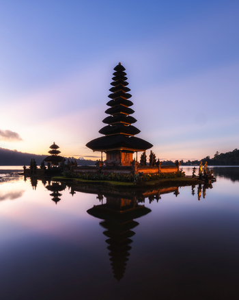 View of a multi tiered pagoda reflecting in the calm still waters under the soft glow of the dawn light Bali Bali Indonesia.