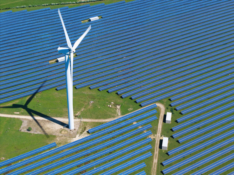 Aerial view of Chelveston Wind Farm featuring rows of blue solar panels and a tall wind turbine on green fields in Wellingborough England United Kingdom. Aerial view of Chelveston Wind Farm featuring rows of blue solar panels and a tall wind turbine on green fields in Wellingborough England United Kingdom.