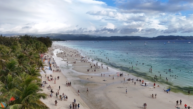 Malay Philippines 02 May 2026 Aerial view of Boracay Island featuring white sand turquoise waters and crowds of people under a cloudy sky.