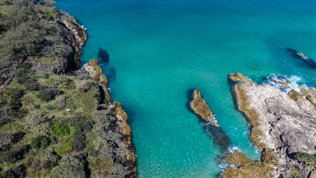 Aerial view of North Stradbroke Island featuring turquoise waters rugged rocky coastline and lush coastal vegetation in Redland City Queensland Australia. Aerial view of North Stradbroke Island featuring turquoise waters rugged rocky coastline and lush coastal vegetation in Redland City Queensland Australia.