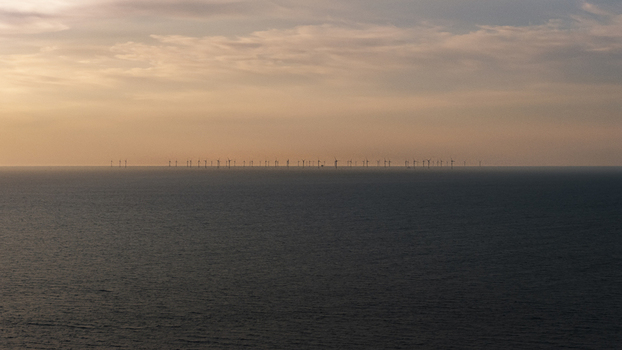 Aerial view of an offshore wind farm in the Atlantic Ocean under a soft sunset sky near the coast of Plevenon Brittany France. Aerial view of an offshore wind farm in the Atlantic Ocean under a soft sunset sky near the coast of Plevenon Brittany France.