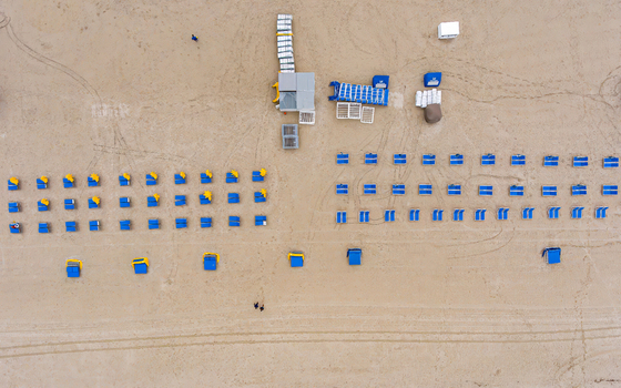 Aerial view of rows of blue and yellow beach chairs and umbrellas on the sandy beach in Miami Florida United States. Aerial view of rows of blue and yellow beach chairs and umbrellas on the sandy beach in Miami Florida United States.