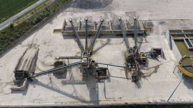 Aerial view of an industrial gravel processing plant with conveyor belts piles of aggregate and water treatment tanks in La Longueville Hauts de France France.