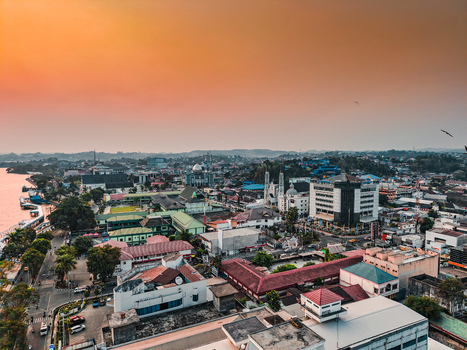 Aerial view of the Samarinda cityscape at sunset featuring the Mahakam River urban architecture and mosques under a warm orange sky in Samarinda East Kalimantan Indonesia. Aerial view of the Samarinda cityscape at sunset featuring the Mahakam River urban architecture and mosques under a warm orange sky in Samarinda East Kalimantan Indonesia.