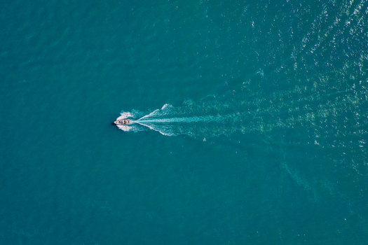 Aerial view of a motorboat with people on board cruising across the turquoise waters of Lake Garda Italy. Aerial view of a motorboat with people on board cruising across the turquoise waters of Lake Garda Italy.