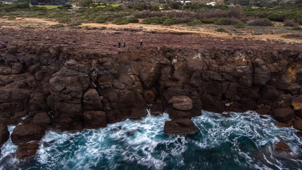 Aerial view of Faraglioni Nido dei Passeri with rugged volcanic rock cliffs and crashing waves along the coastline in Calasetta Sardinia Italy. Aerial view of Faraglioni Nido dei Passeri with rugged volcanic rock cliffs and crashing waves along the coastline in Calasetta Sardinia Italy.