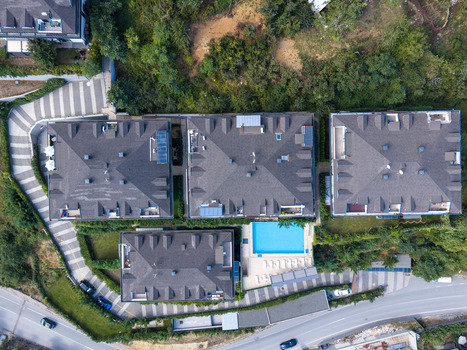 Aerial view of modern residential buildings with dark shingled roofs and a bright blue swimming pool surrounded by lush greenery and paved driveways in Istanbul Istanbul Turkiye. Aerial view of modern residential buildings with dark shingled roofs and a bright blue swimming pool surrounded by lush greenery and paved driveways in Istanbul Istanbul Turkiye.