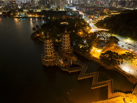 Aerial view of the illuminated Dragon and Tiger Pagodas at Lotus Pond with a zigzag bridge surrounding parkland and city lights at night in Kaohsiung Taiwan. Aerial view of the illuminated Dragon and Tiger Pagodas at Lotus Pond with a zigzag bridge surrounding parkland and city lights at night in Kaohsiung Taiwan.