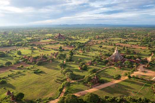 Aerial view of ancient Buddhist temples and pagodas scattered across lush green plains under a soft morning sky Old Bagan Mandalay Region Myanmar Burma. Aerial view of ancient Buddhist temples and pagodas scattered across lush green plains under a soft morning sky Old Bagan Mandalay Region Myanmar Burma.
