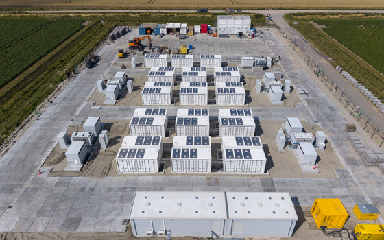 Aerial view of the Battery Energy Storage System at Wind Park with rows of white battery containers on a concrete pad surrounded by agricultural fields in Dronten Flevoland Netherlands. Aerial view of the Battery Energy Storage System at Wind Park with rows of white battery containers on a concrete pad surrounded by agricultural fields in Dronten Flevoland Netherlands.