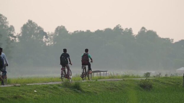 View of two people riding bicycles on a rural path Bangladesh.