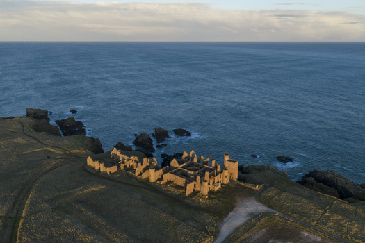 Aerial view of the historic ruins of Slains Castle perched on rugged coastal cliffs overlooking the North Sea in Cruden Bay Scotland United Kingdom. Aerial view of the historic ruins of Slains Castle perched on rugged coastal cliffs overlooking the North Sea in Cruden Bay Scotland United Kingdom.