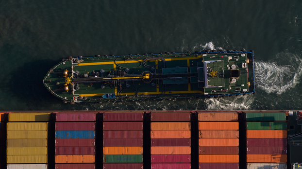 Aerial view of a large container ship with colorful cargo containers and a service vessel alongside in the dark sea Hong Kong Hong Kong. Aerial view of a large container ship with colorful cargo containers and a service vessel alongside in the dark sea Hong Kong Hong Kong.