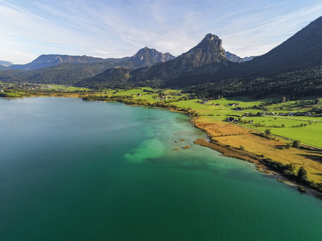 Aerial view of Ochsenkreuz overlooking the turquoise waters of the lake with lush green meadows and mountain peaks in the background Salzburg Umgebung Salzburg Austria.
