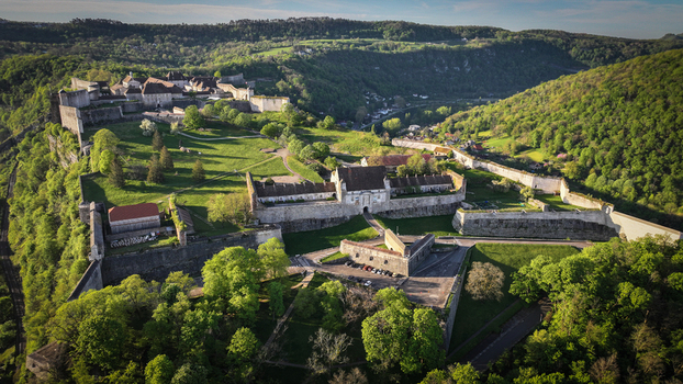 Aerial view of the historic Besancon Citadel with its massive stone fortifications and lush green hills under bright sunlight in Besancon Bourgogne Franche Comte France. Aerial view of the historic Besancon Citadel with its massive stone fortifications and lush green hills under bright sunlight in Besancon Bourgogne Franche Comte France.