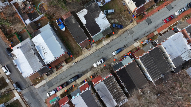 Aerial view of a residential street featuring rows of houses with various roof types parked cars along the road and bare trees in a suburban neighborhood in Chester Pennsylvania United States. Aerial view of a residential street featuring rows of houses with various roof types parked cars along the road and bare trees in a suburban neighborhood in Chester Pennsylvania United States.