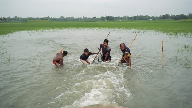 View of men fishing in a flooded field in Bogura Bangladesh.