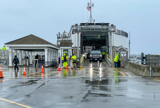 Edgartown United States 14 May 2026 View of the ferry terminal at Martha s Vineyard with workers in yellow rain gear directing a vehicle off the boat on an overcast day.