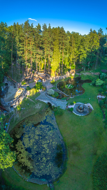 Aerial view of a landscaped park with ponds stone bridges and stone structures surrounded by a dense forest in Latvia. Aerial view of a landscaped park with ponds stone bridges and stone structures surrounded by a dense forest in Latvia.