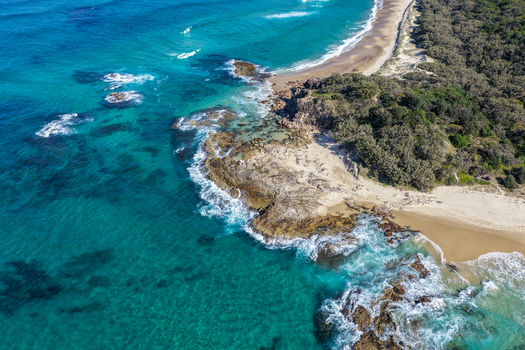 Aerial view of North Stradbroke Island featuring rocky coastline turquoise ocean waves sandy beach and coastal vegetation in Redland City Queensland Australia. Aerial view of North Stradbroke Island featuring rocky coastline turquoise ocean waves sandy beach and coastal vegetation in Redland City Queensland Australia.