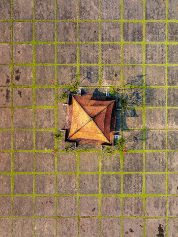 Aerial view of a traditional building with a terracotta roof centered in a geometric stone courtyard with grass filled grid lines in Vietnam. Aerial view of a traditional building with a terracotta roof centered in a geometric stone courtyard with grass filled grid lines in Vietnam.