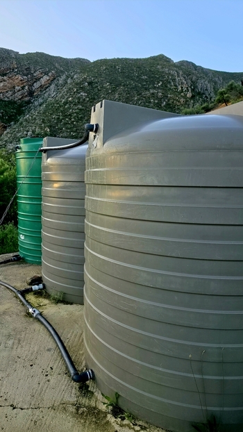 View of large plastic water storage tanks connected by pipes on a farm with a mountain backdrop in Hoeko Western Cape South Africa. View of large plastic water storage tanks connected by pipes on a farm with a mountain backdrop in Hoeko Western Cape South Africa.